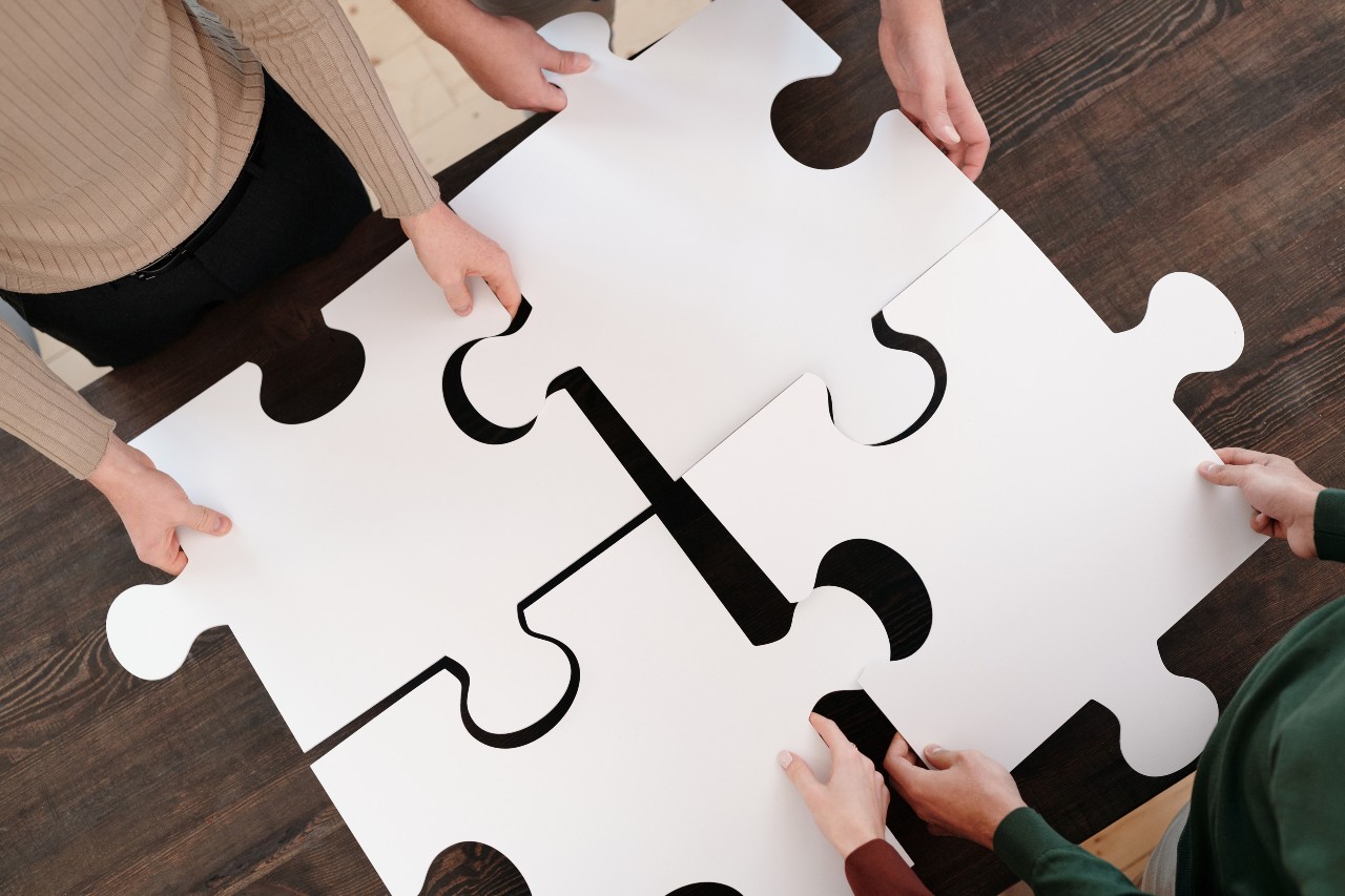 people holding large pieces of a jigsaw